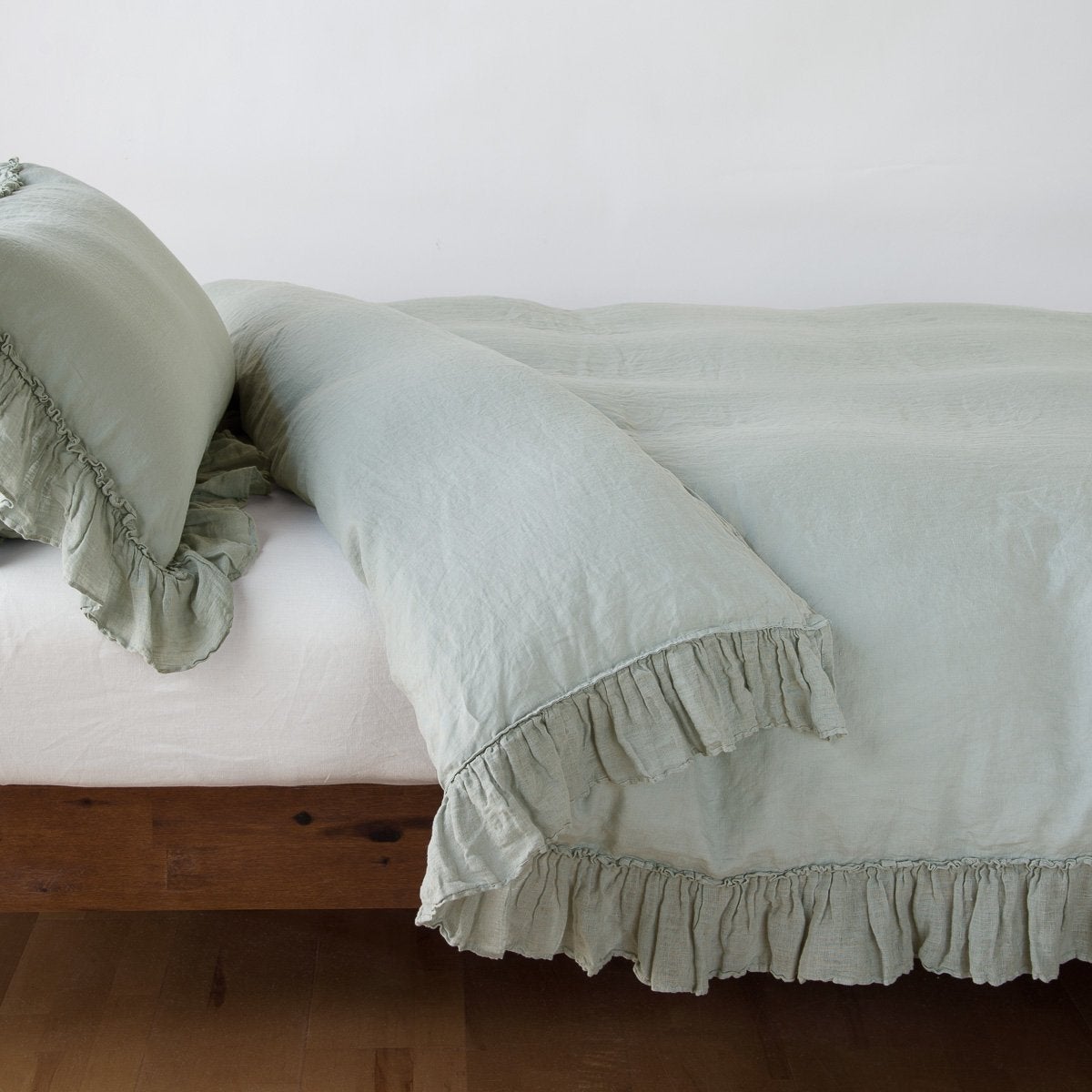 Bella Notte Linen Whisper duvet cover in Eucalyptus, showing ruffled hem detail on bed.