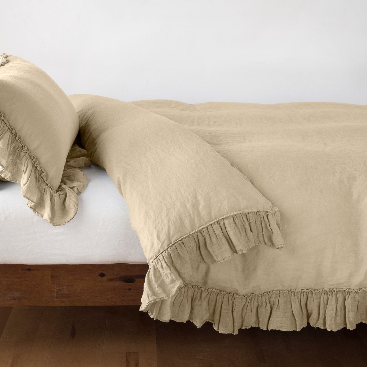 Ruffled hem detail on Bella Notte Linen Whisper duvet cover in Honeycomb on a wood bed frame.