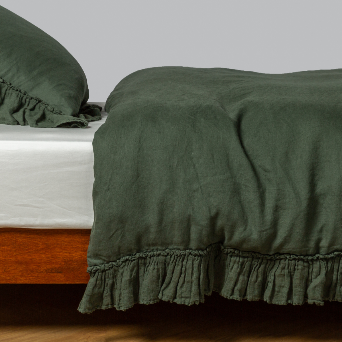 Juniper ruffled linen duvet cover and pillowcase styled on a wooden bed frame.