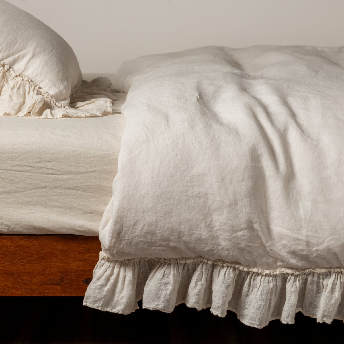 Ruffled hem detail on Bella Notte Linen Whisper duvet cover in Natural on wood bed frame.
