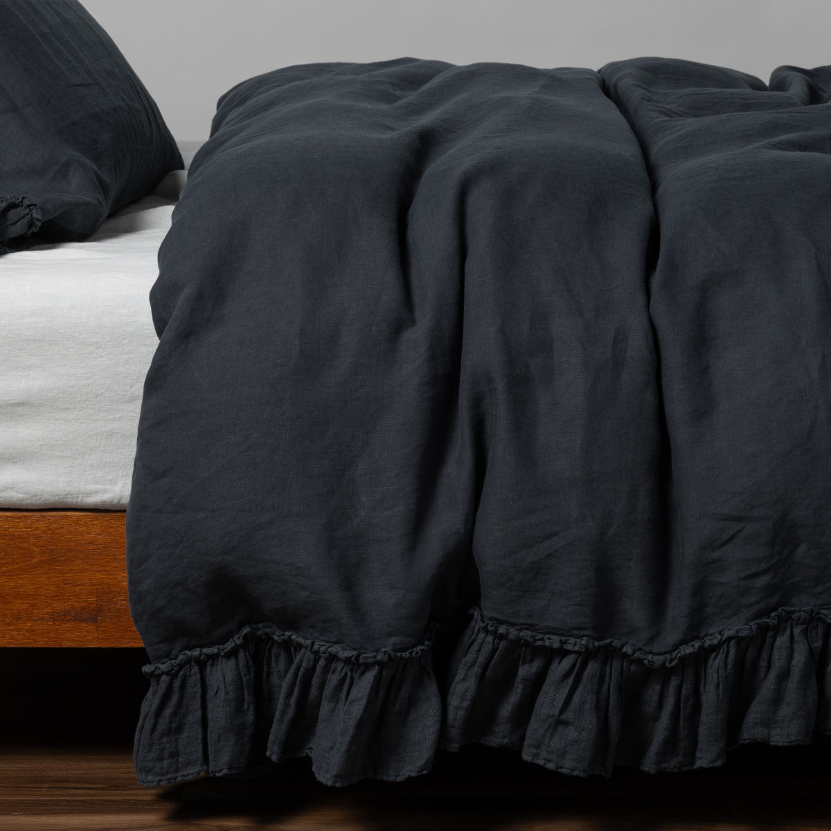 Bella Notte Linen Whisper duvet cover in Slate, showing ruffled hem detail draped over bed foot.