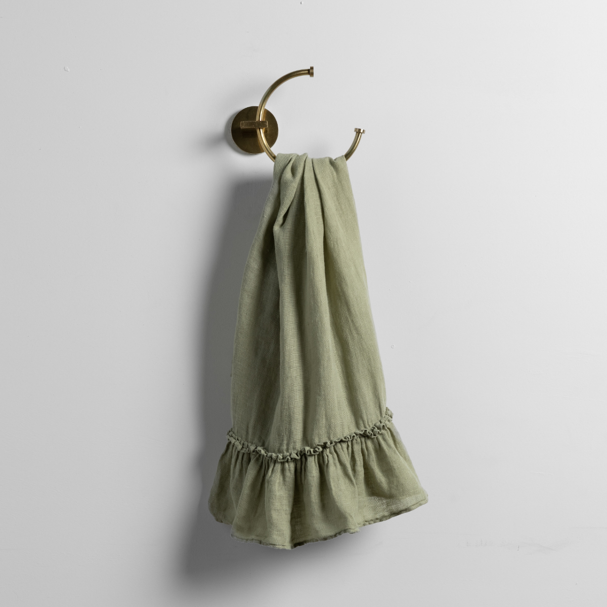 Desert Sage guest towel with ruffled hem, draped over a brass hook.