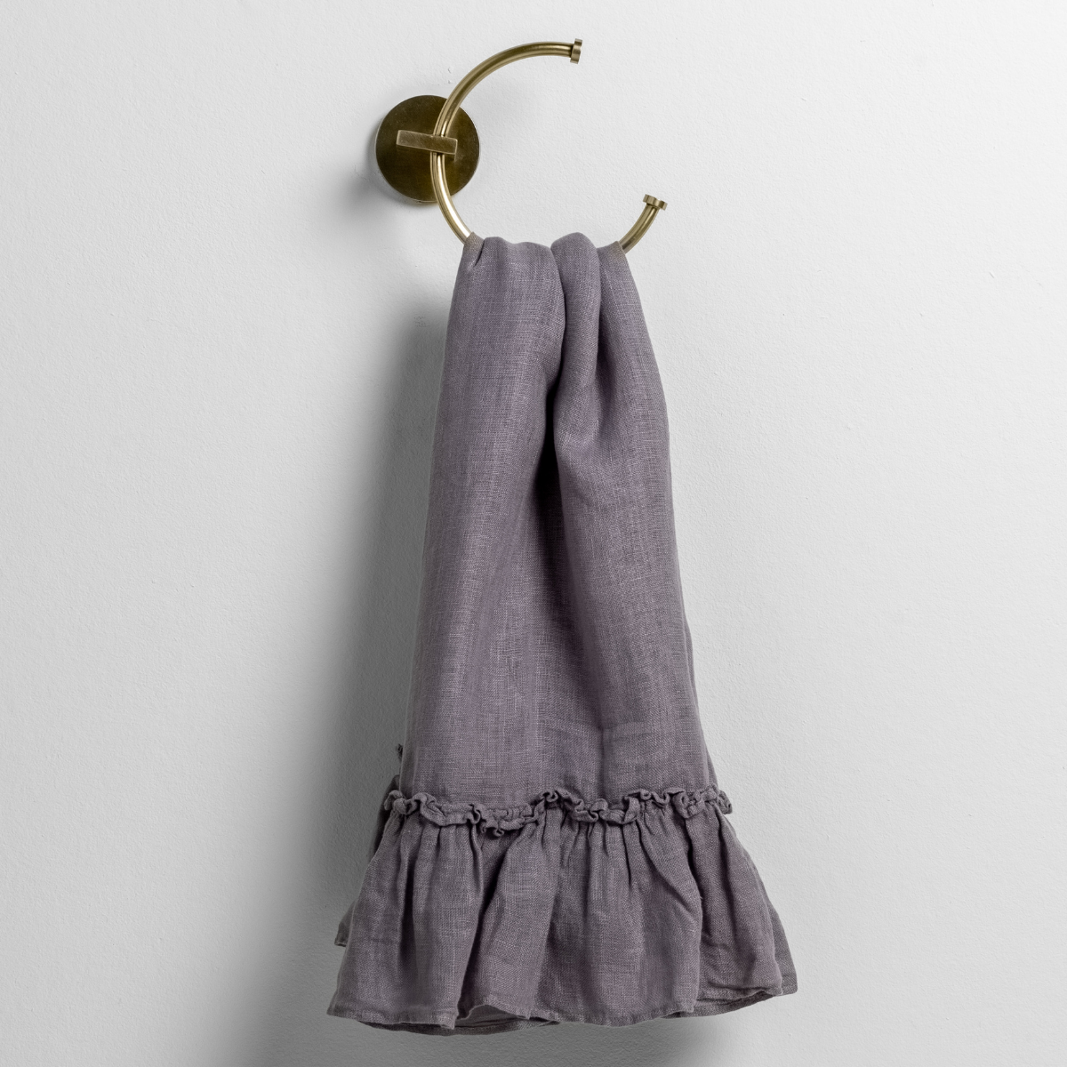 Bella Notte Linen Whisper guest towel in French Lavender, draped on brass ring, ruffled hem detail.