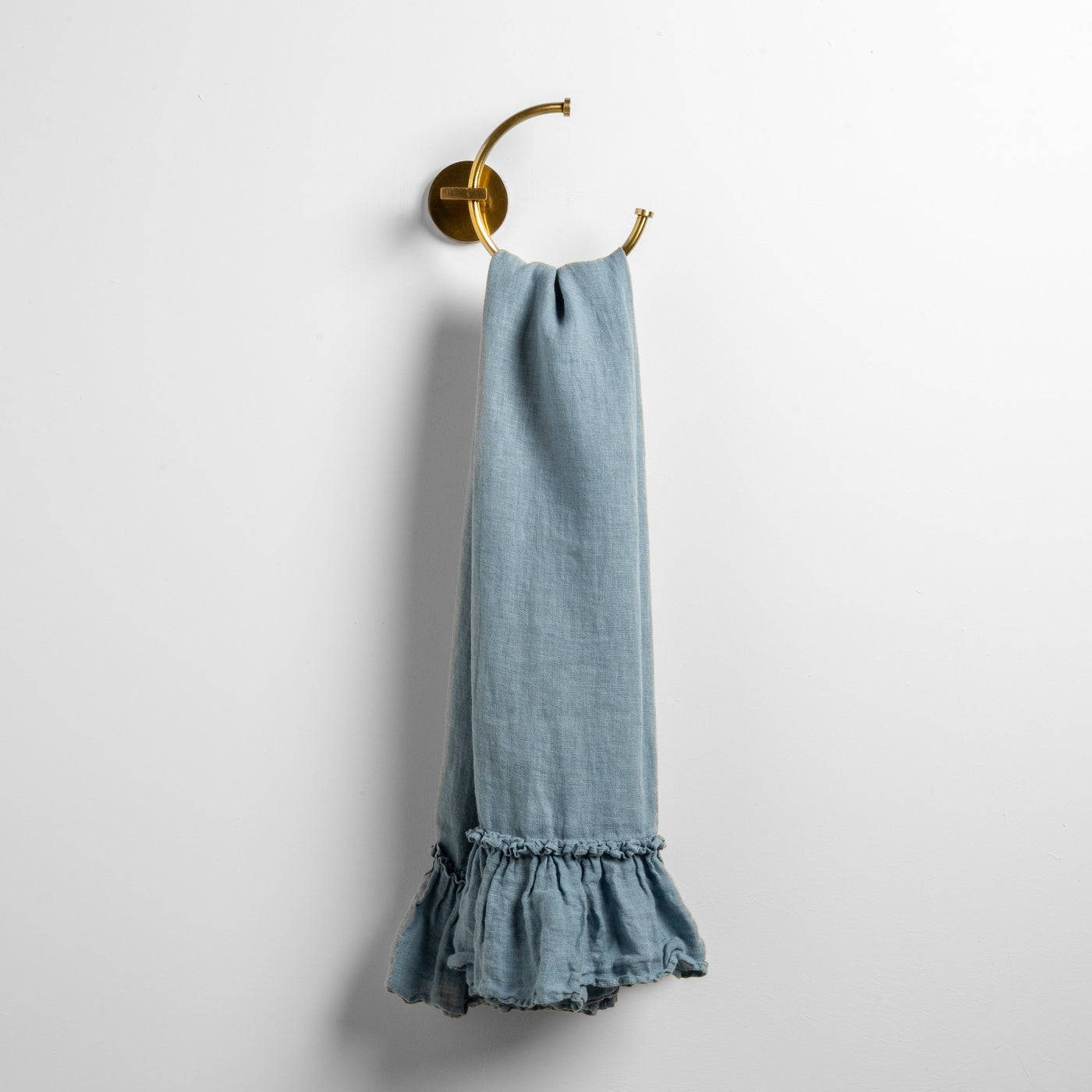 Bella Notte Linen Whisper guest towel in Tahoe Blue, ruffled hem detail, hung on brass ring.