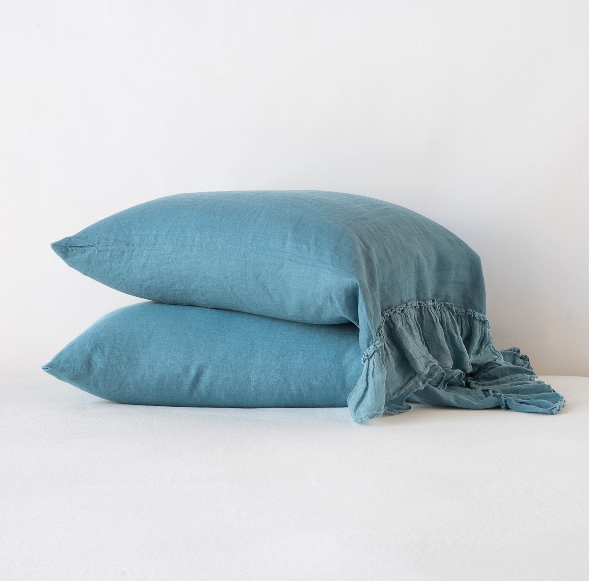 Bella Notte Linen Whisper pillowcases in Cenote, stacked pair with ruffled edge detail.