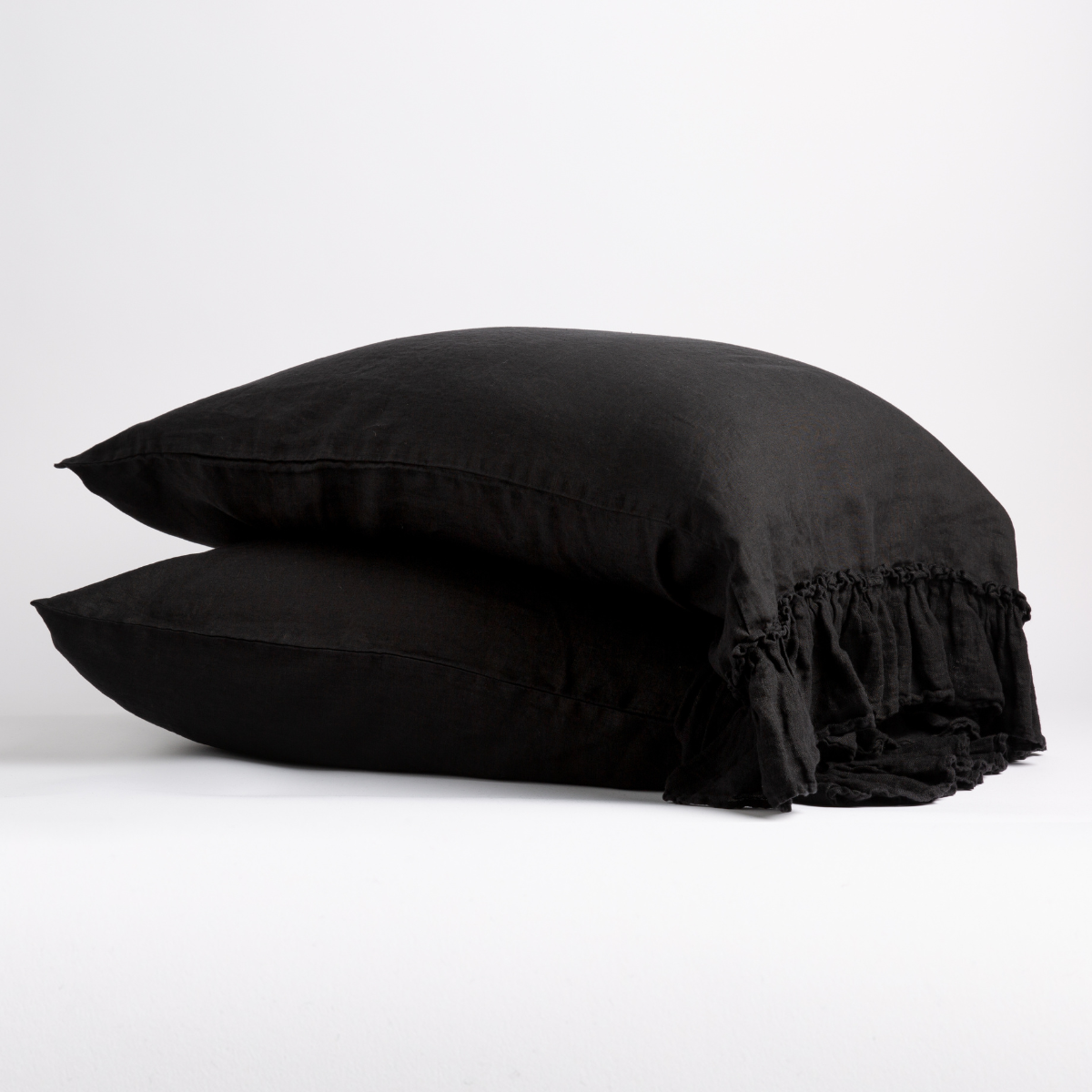 Two Corvino Bella Notte Linen Whisper pillowcases stacked, showing delicate ruffle trim detail.