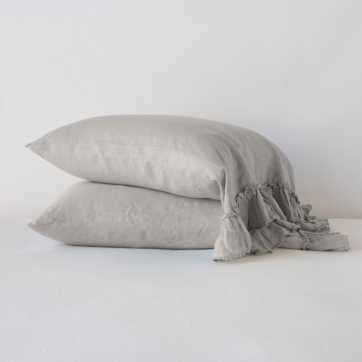 Two Fog linen pillowcases stacked, ruffled trim detail visible on white surface.
