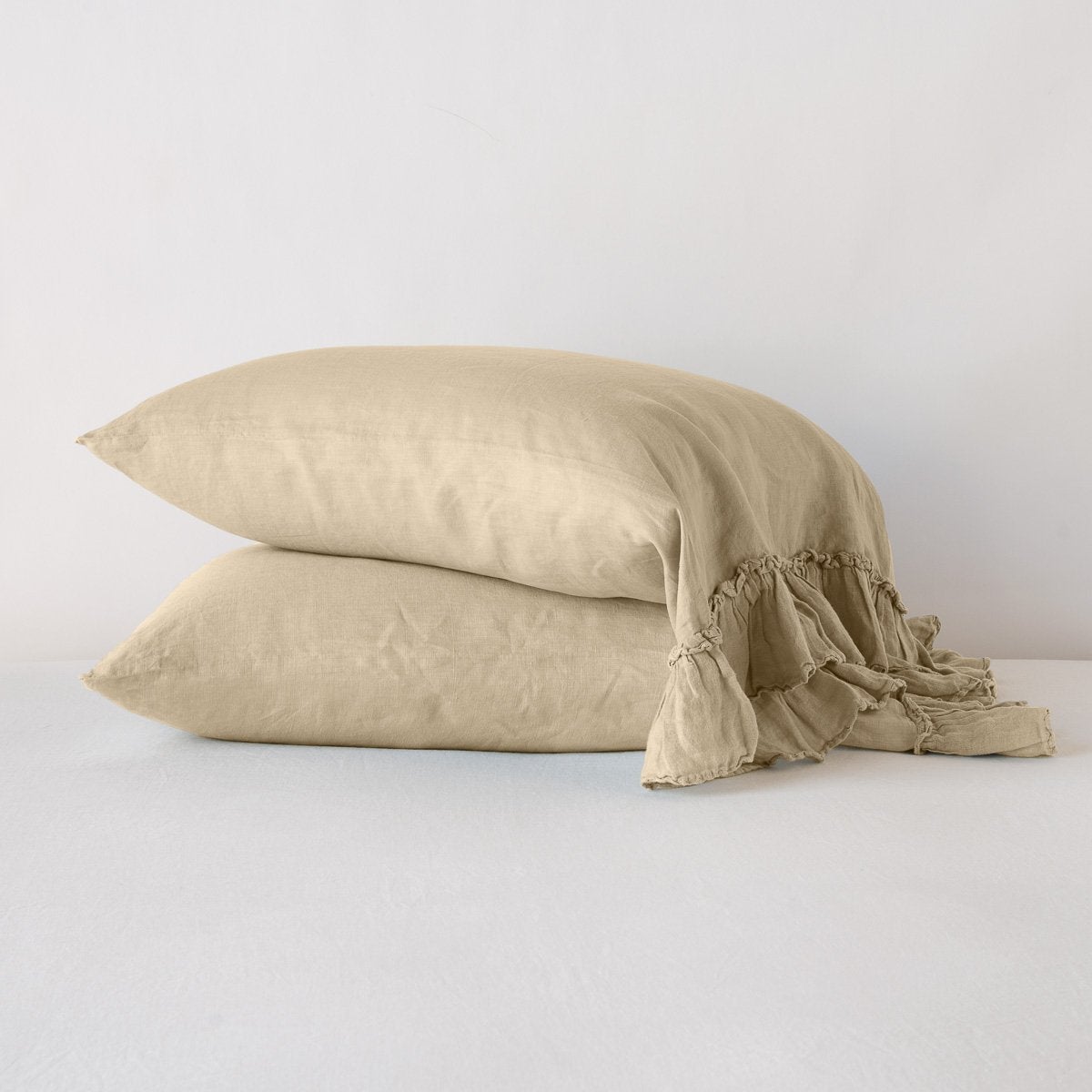 Two stacked Honeycomb linen pillowcases with ruffled edge detail on white bedding.