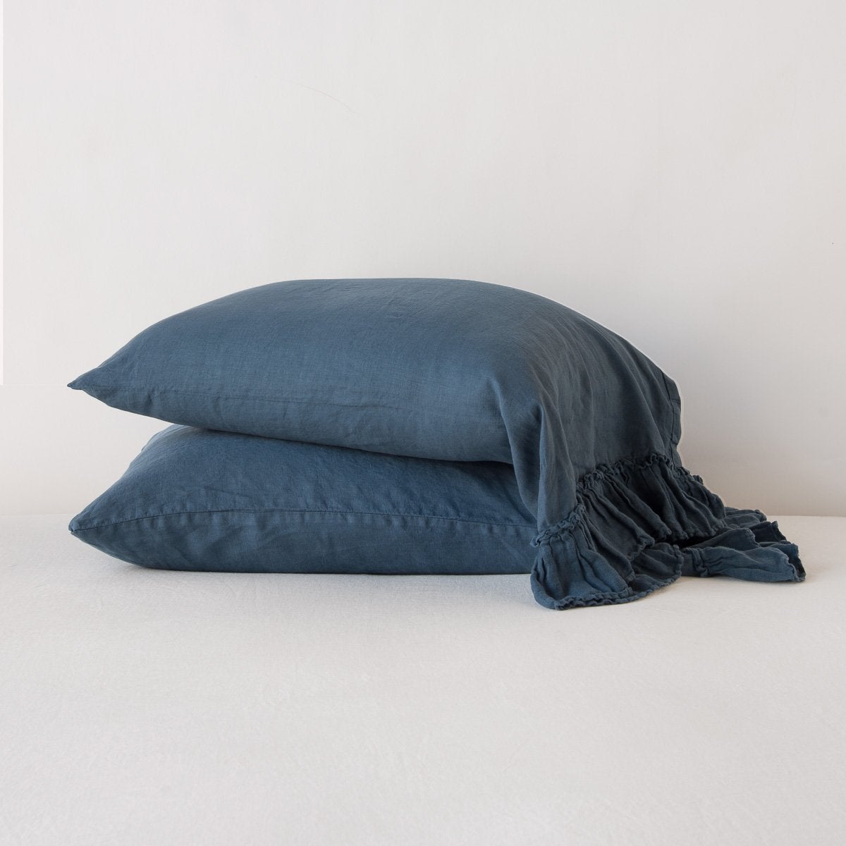 Two stacked Midnight linen pillowcases with ruffled edge detail, soft relaxed texture.