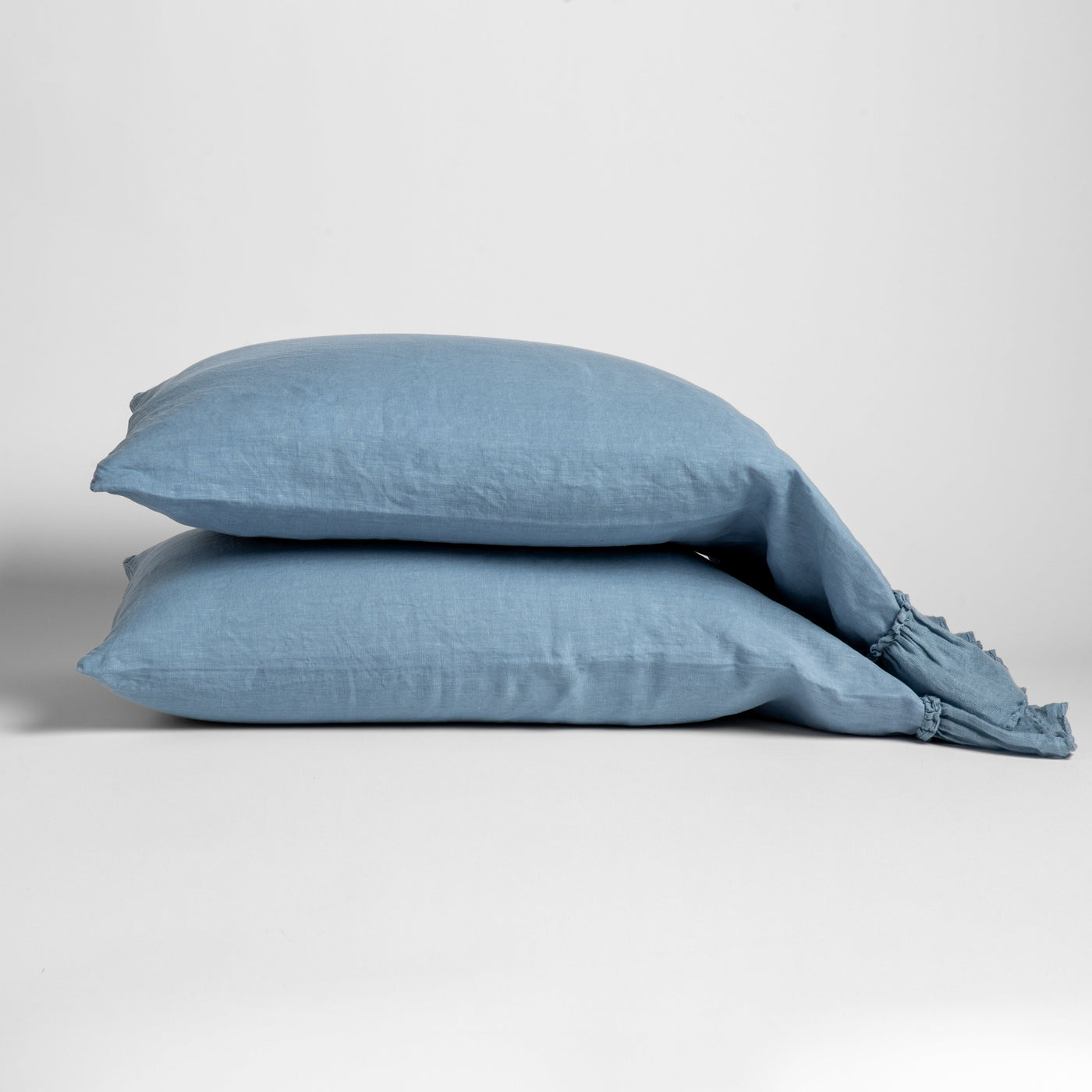 Two Bella Notte Linen Whisper pillowcases stacked in Tahoe Blue with frayed trim detail.
