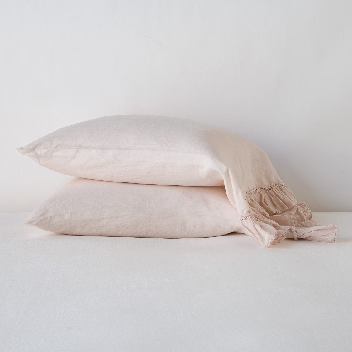 Two stacked Pearl Bella Notte Linen Whisper pillowcases with ruffled edge detail.