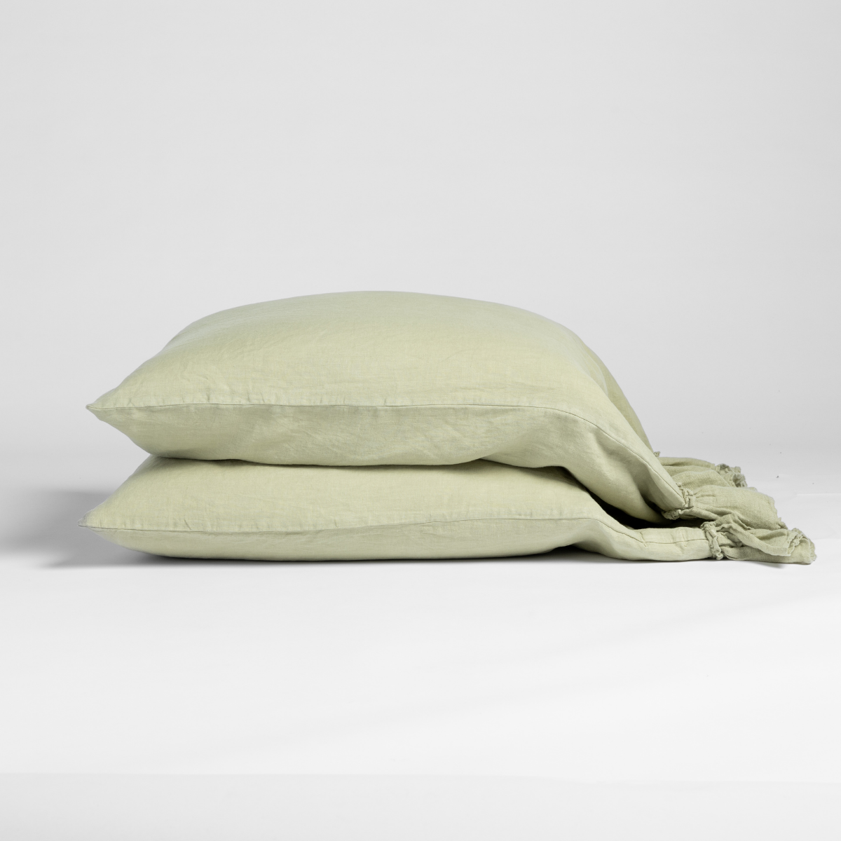 Folded Desert Sage linen pillowcase pair stacked, showing relaxed texture and casual drape.