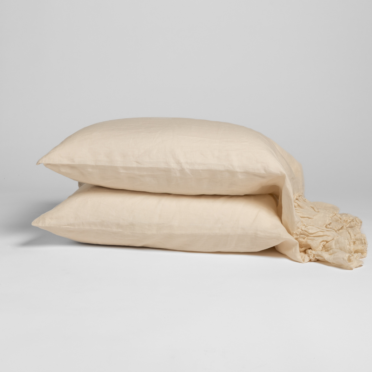 Two Natural linen pillowcases stacked, showing soft drape and relaxed texture against grey background.