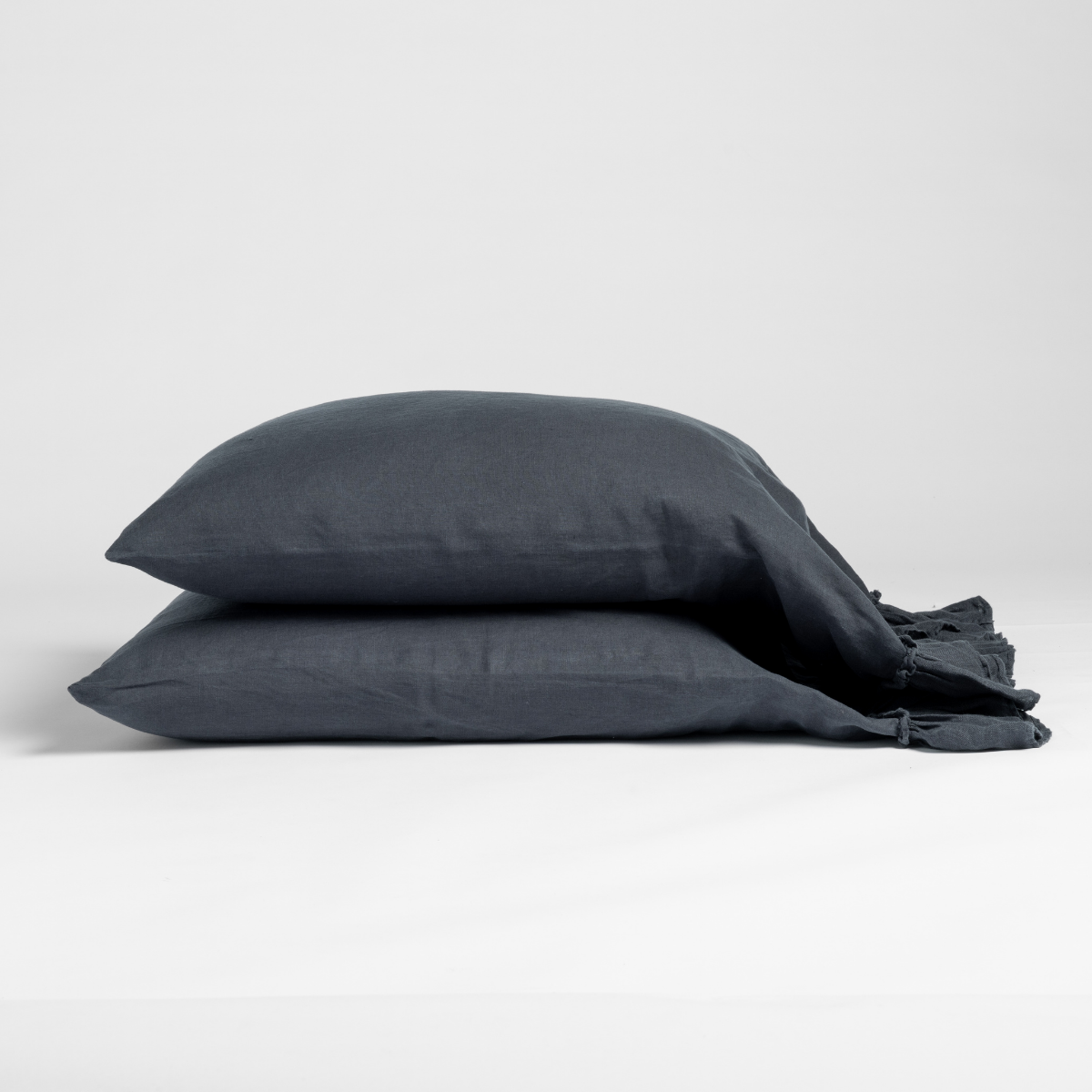 Two stacked Slate linen pillowcases with relaxed drape and visible tie closures.
