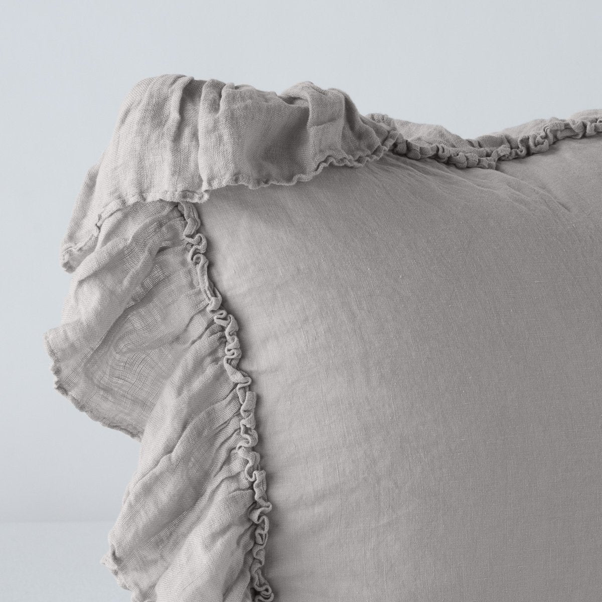Corner detail of a Fog linen sham with delicate ruffled trim along the edges.