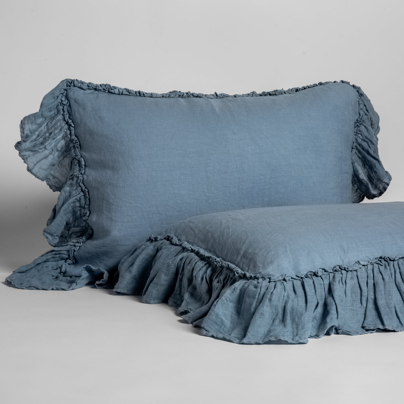 Ruffled linen pillow shams in Tahoe Blue, stacked and styled, showing gathered trim detail.