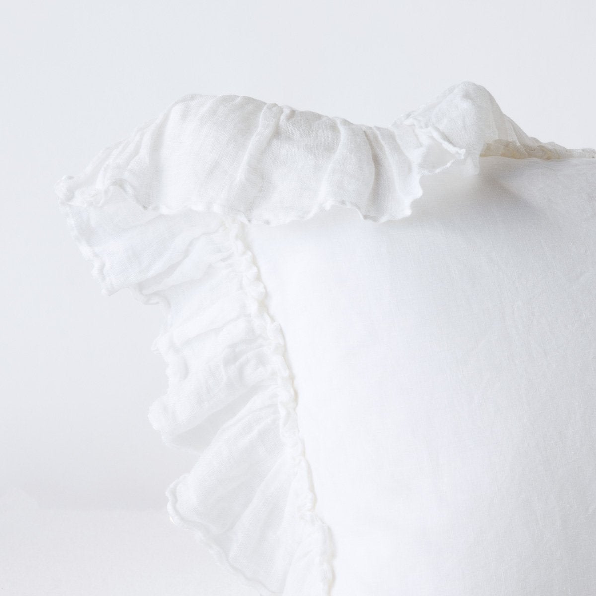 Close-up of White linen sham corner with delicate ruffled trim detail.