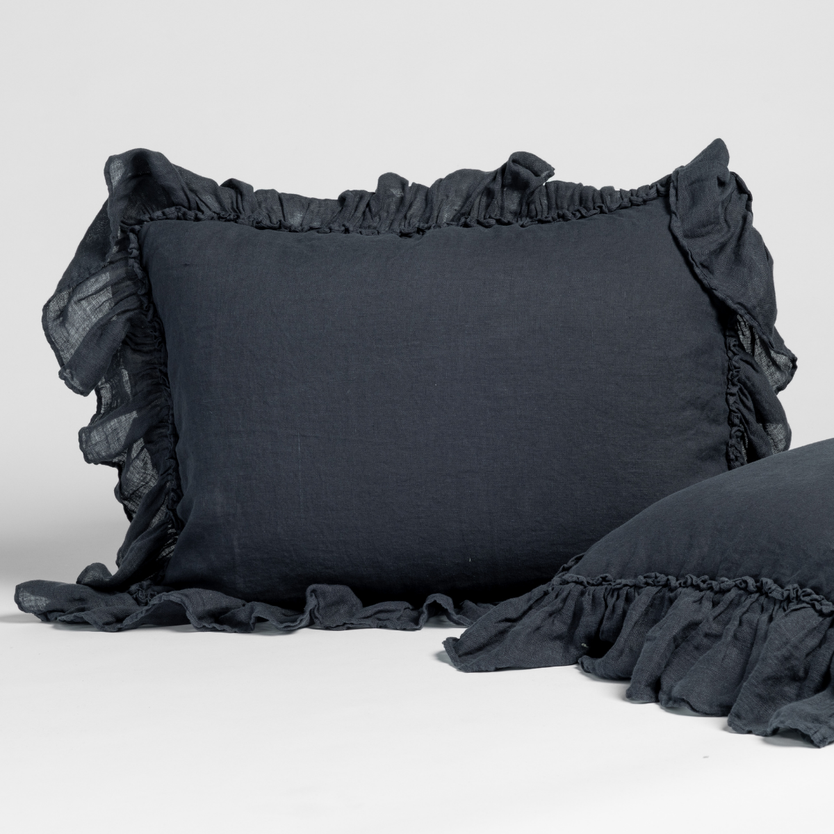 Ruffled edges detail on Bella Notte Linen Whisper sham in Slate, two pillows styled.
