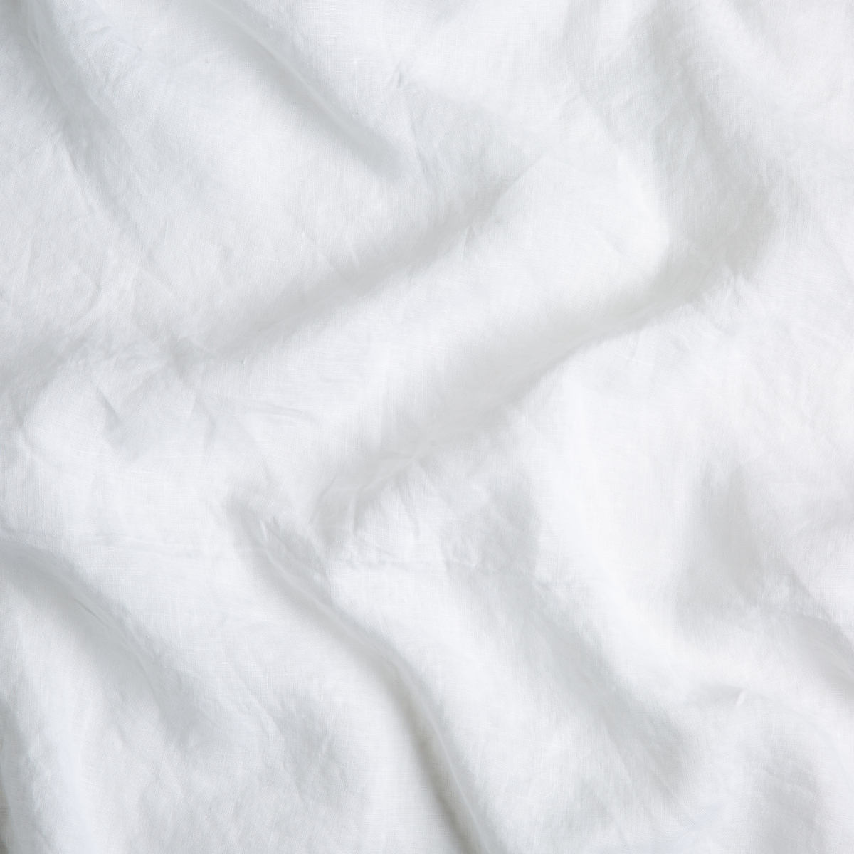 Close-up of draped white linen fabric showing soft wrinkled texture.