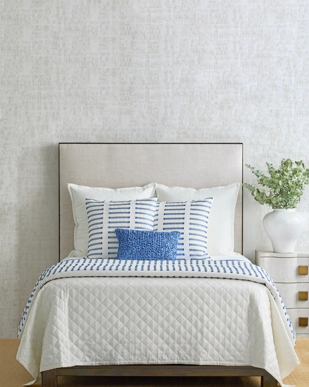 Ivory quilted coverlet on a styled bed with blue and white accent pillows.