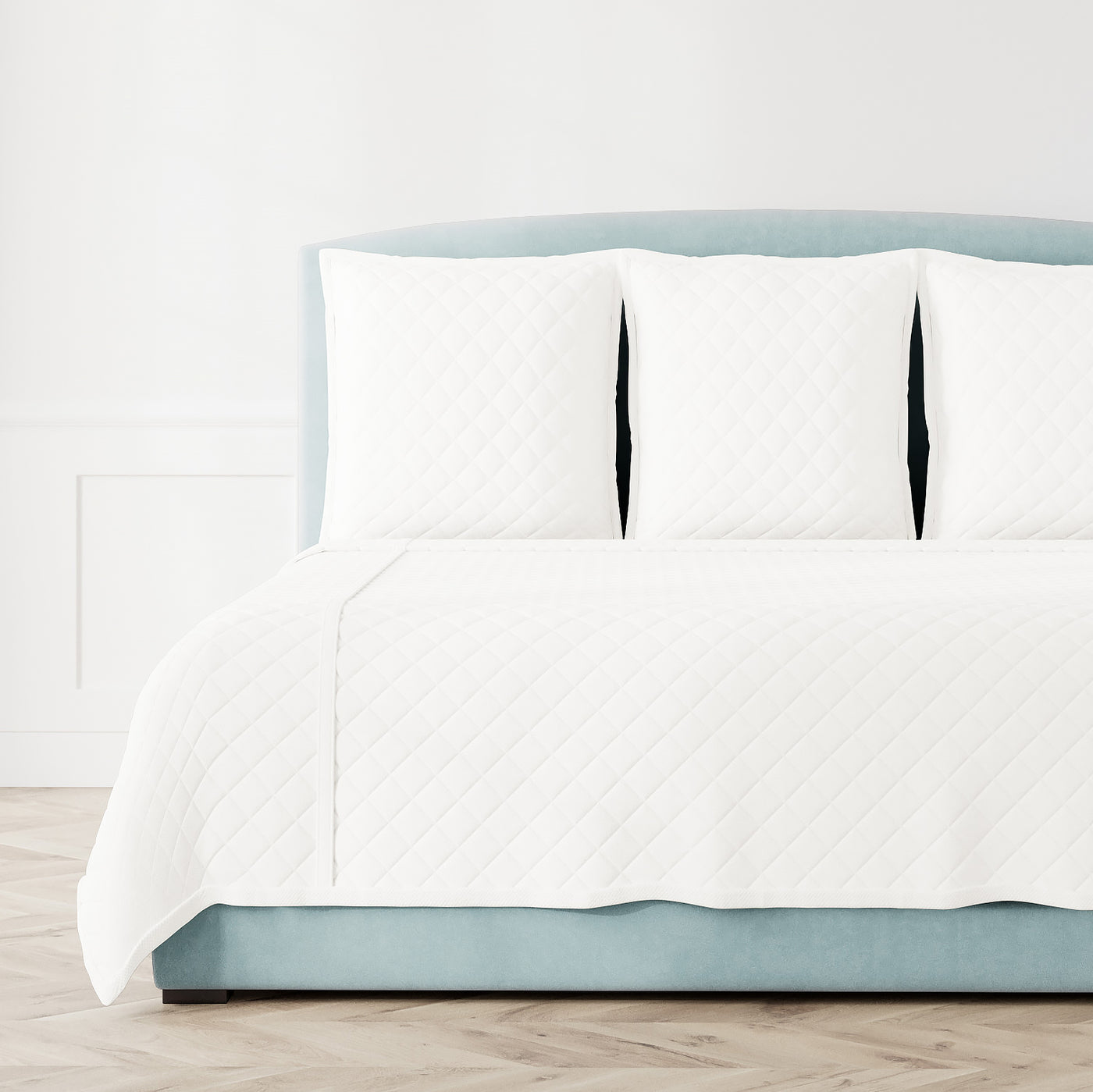 Ann Gish Linen quilted coverlet in white on a styled bed with matching shams.