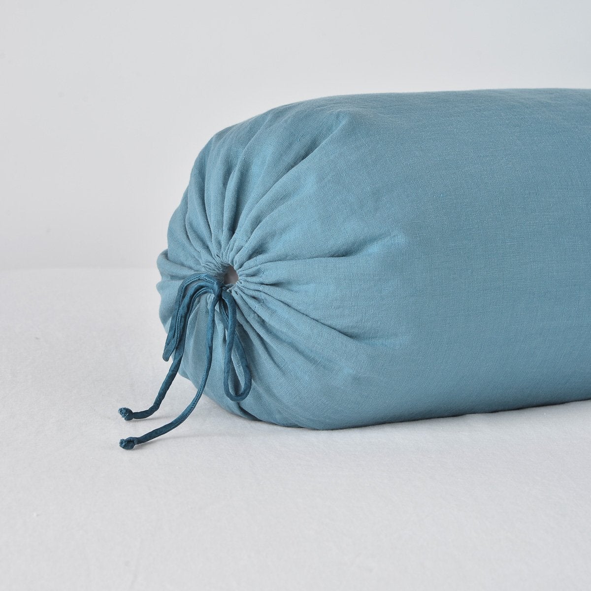 Close-up of Cenote linen bolster pillow end with gathered drawstring closure detail.