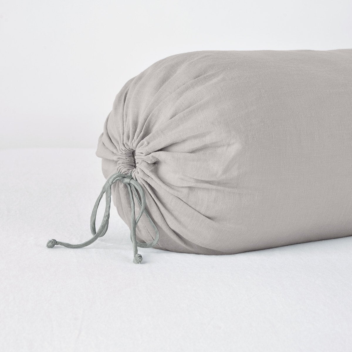 Close-up of Fog linen bolster pillow with gathered drawstring end detail.