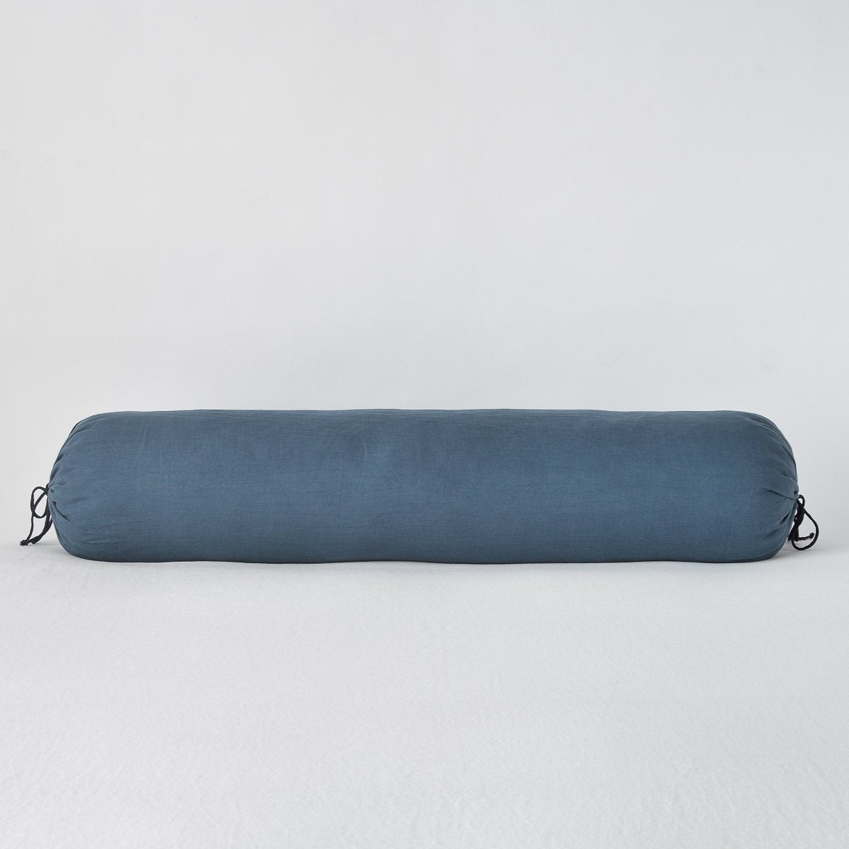 Bella Notte Linen bolster in Midnight, cylindrical with black tassel ties at each end.