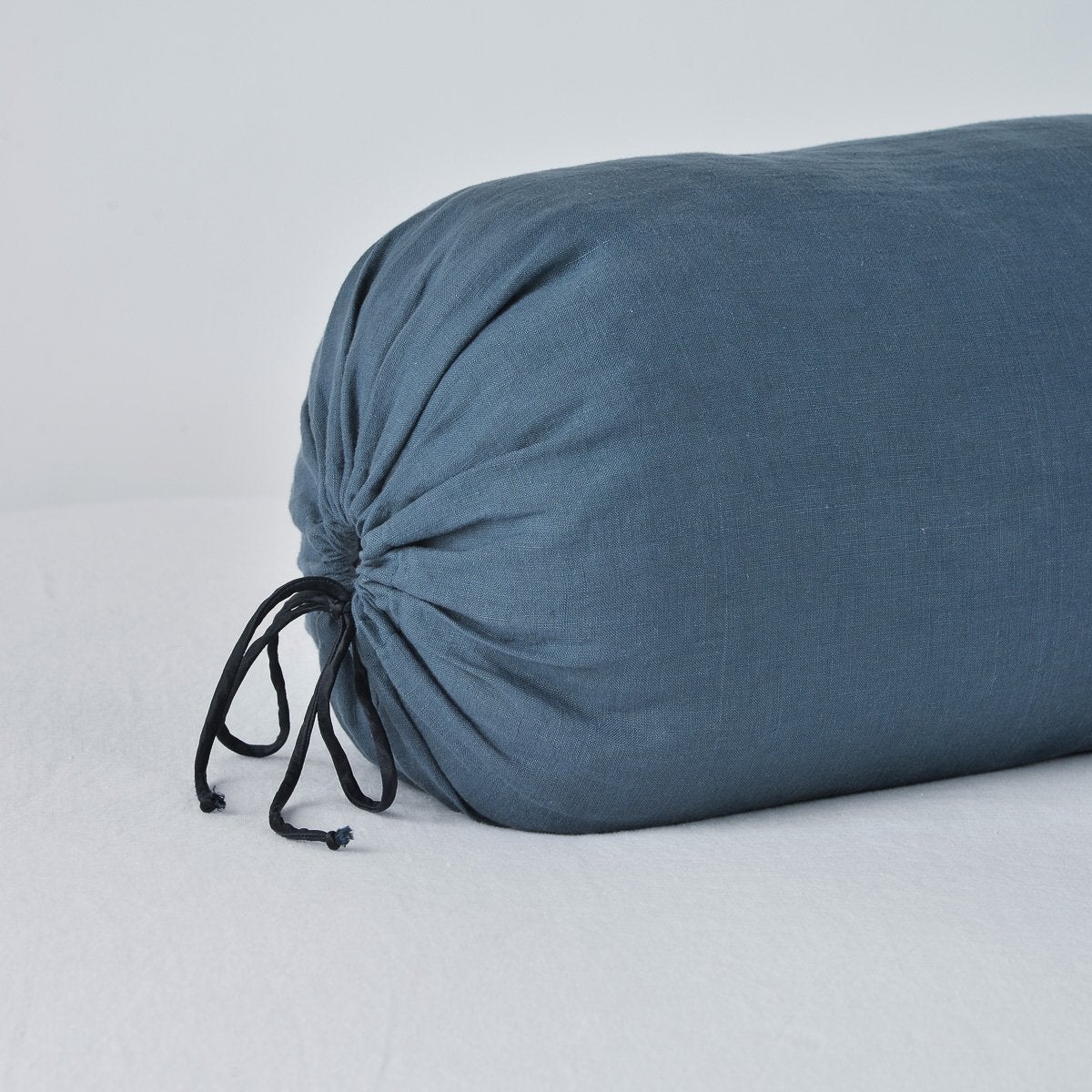 Close-up of Bella Notte Midnight linen bolster pillow with black drawstring tie detail.