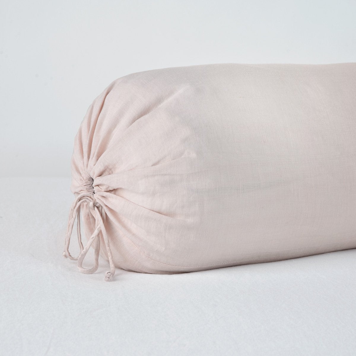 Close-up of Pearl linen bolster pillow with gathered tie closure at end.