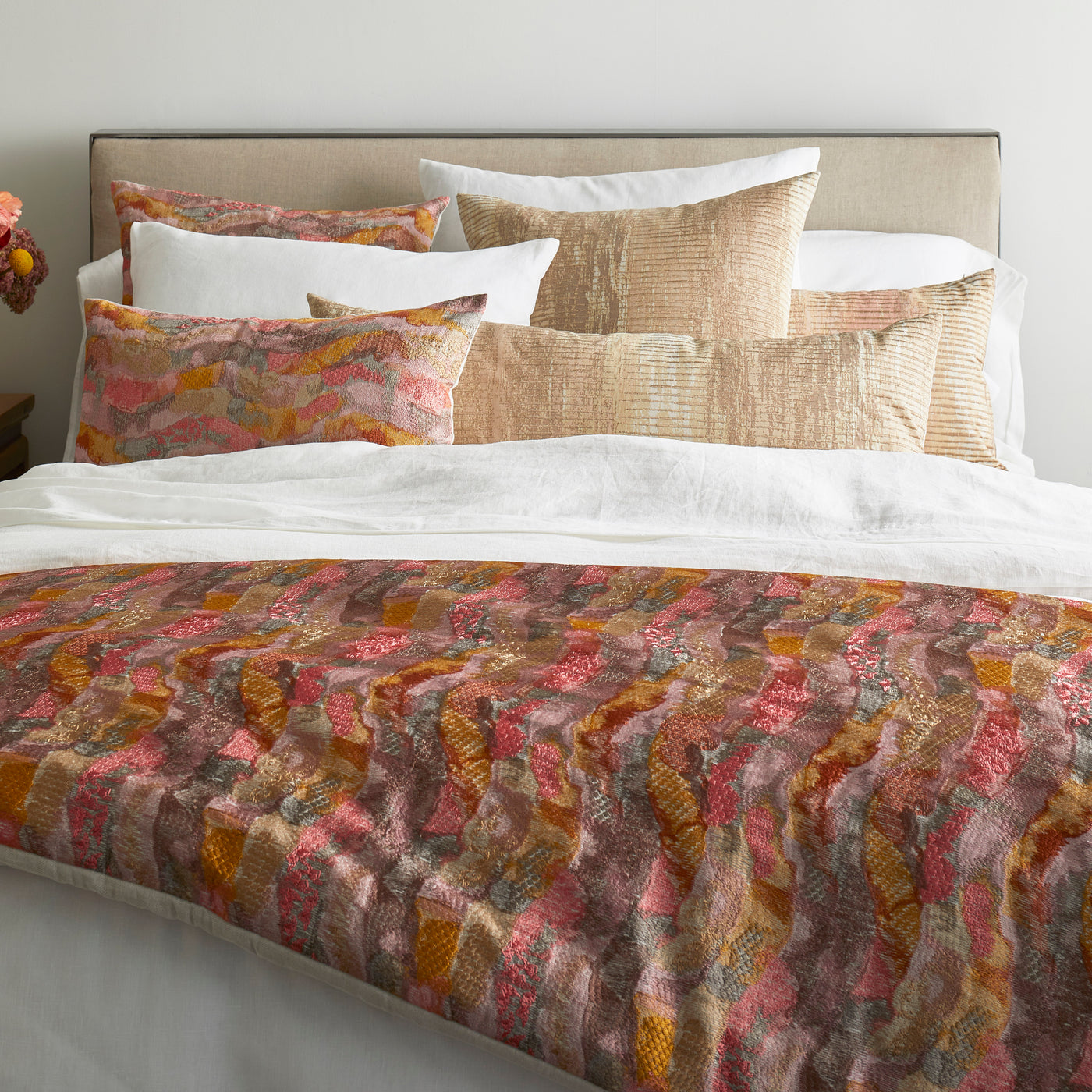 Ann Gish Linen duvet set draped over bed, abstract coral, pink, and amber patchwork pattern.