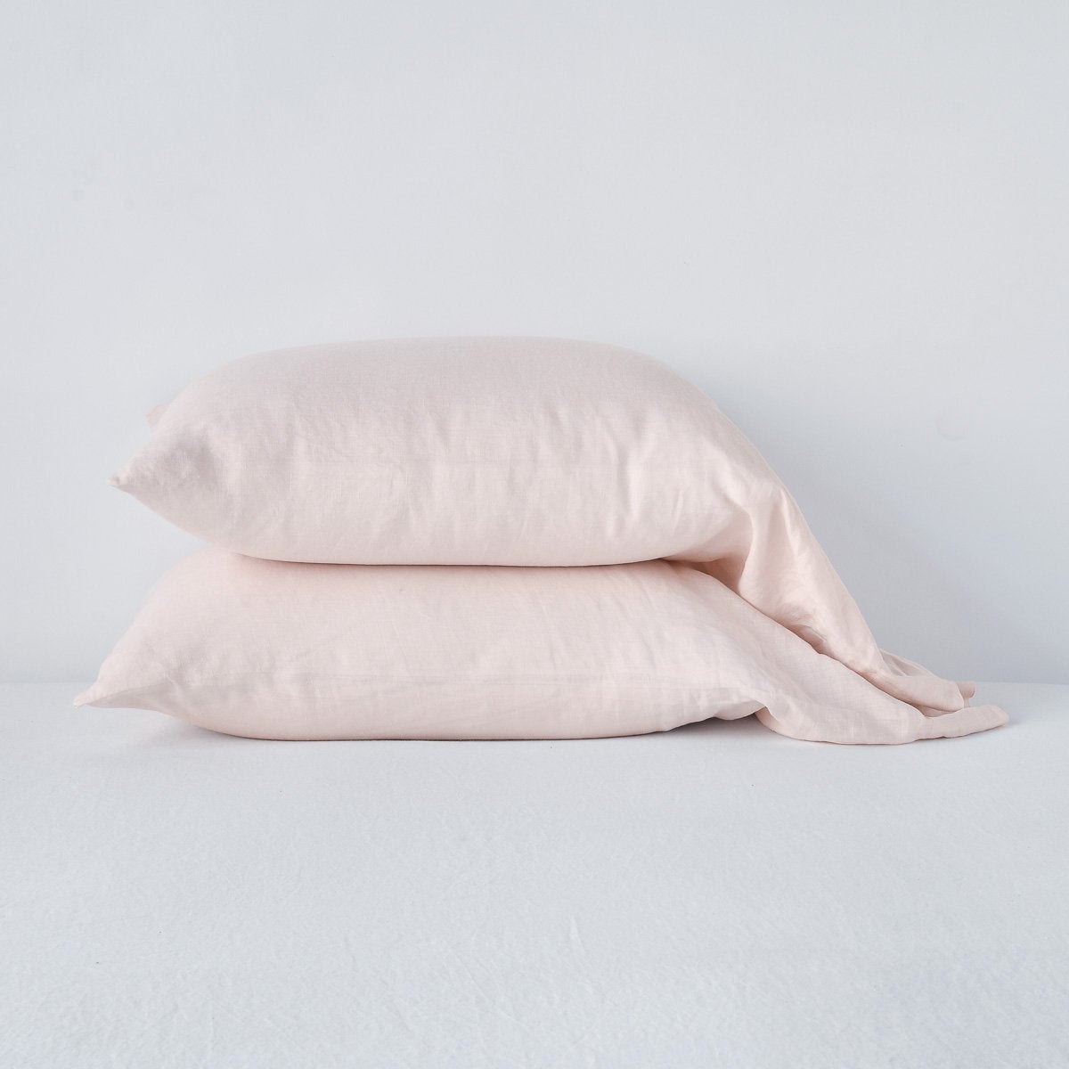 Bella Notte Pearl linen pillowcases stacked in pairs on a white surface.