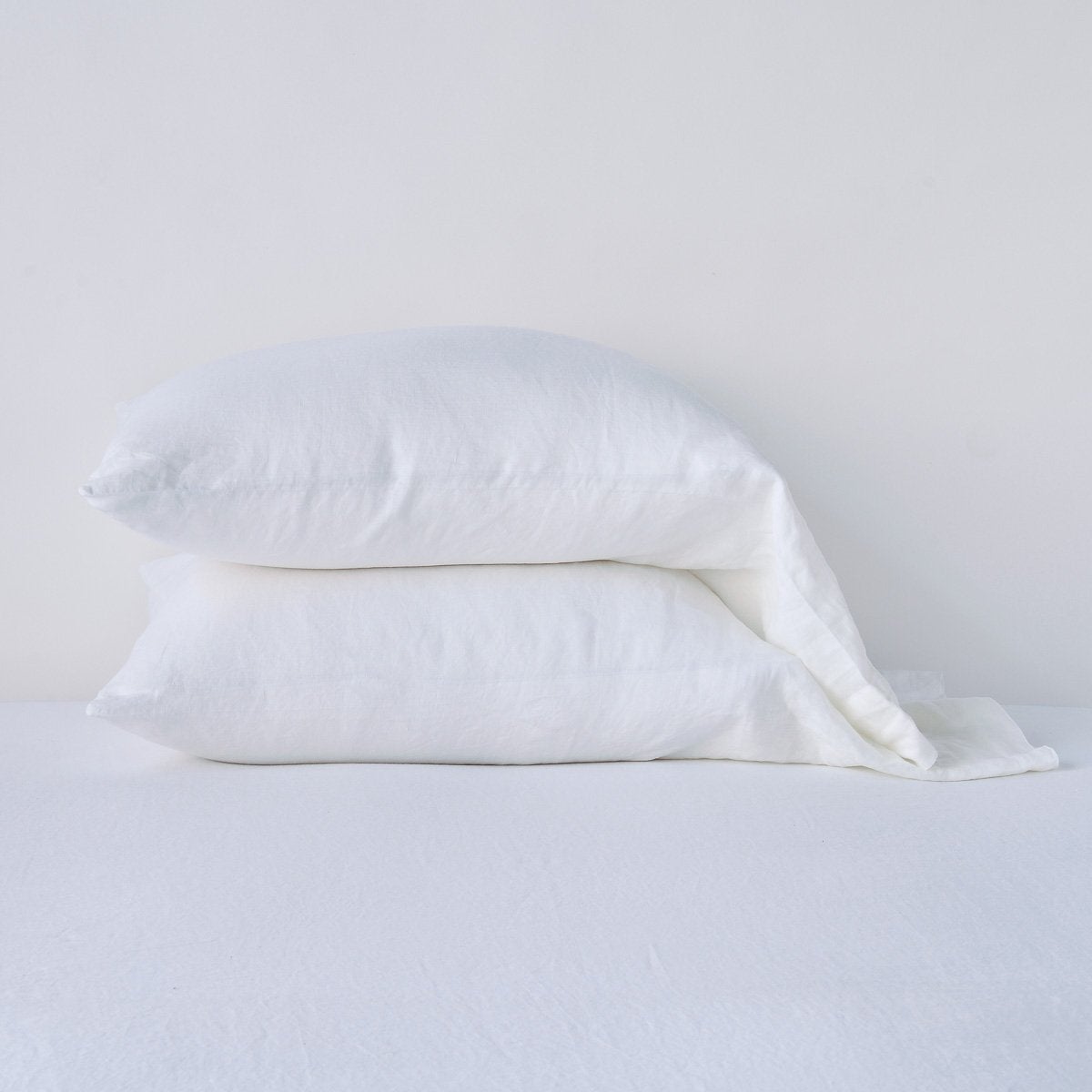 Bella Notte Linen pillowcase in White, two stacked on a white linen surface.