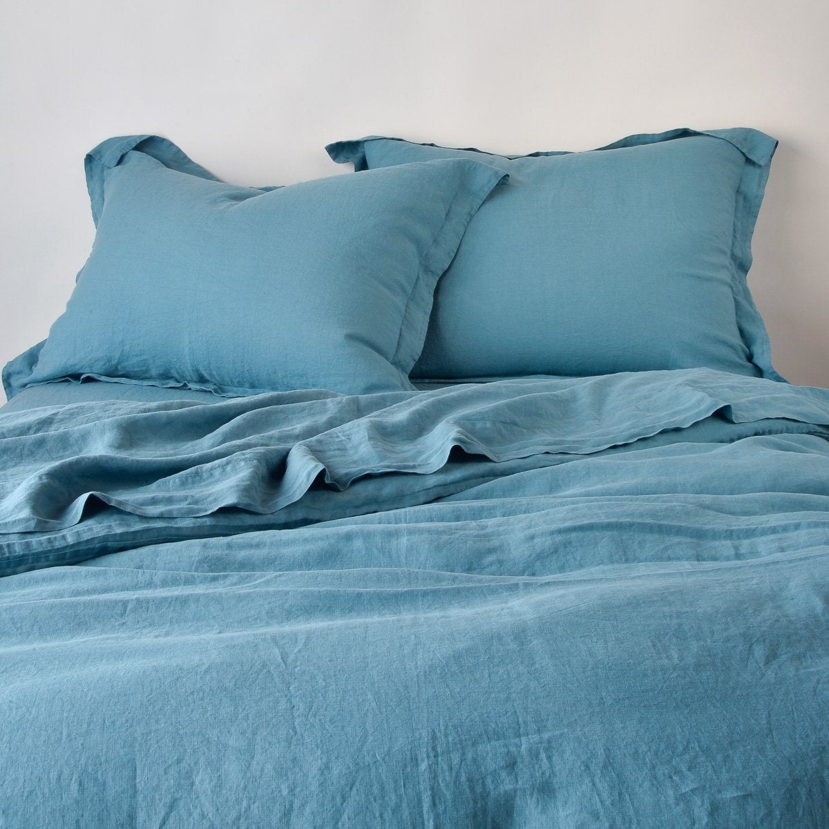 Cenote linen sham styled on a made bed with matching duvet and pillows.