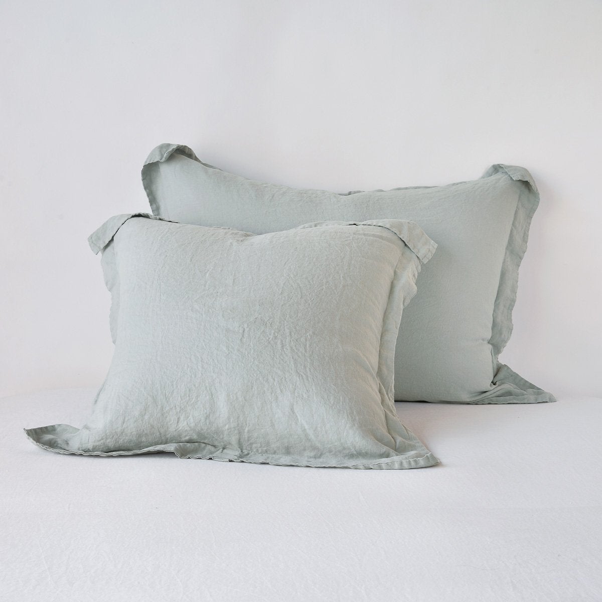 Eucalyptus linen shams stacked, showing relaxed texture and frayed ruffle edge detail.