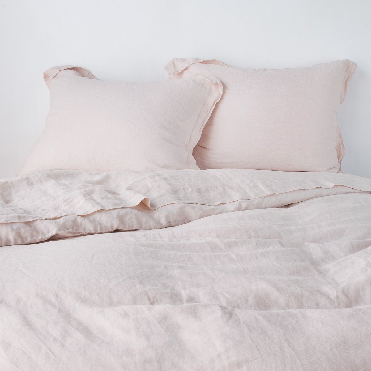 Bella Notte Pearl linen sham styled on bed with duvet, showing relaxed drape and texture.