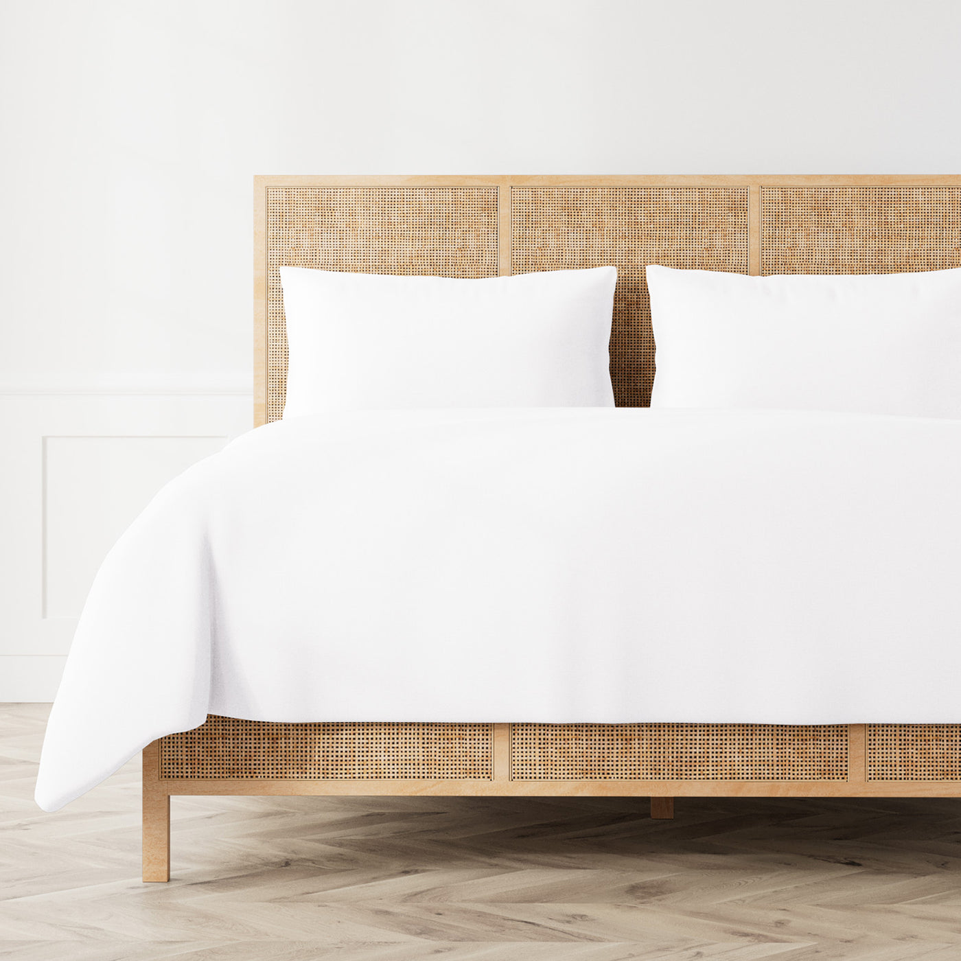 Ann Gish Linen duvet set in white, styled on a rattan bed with matching pillow shams.