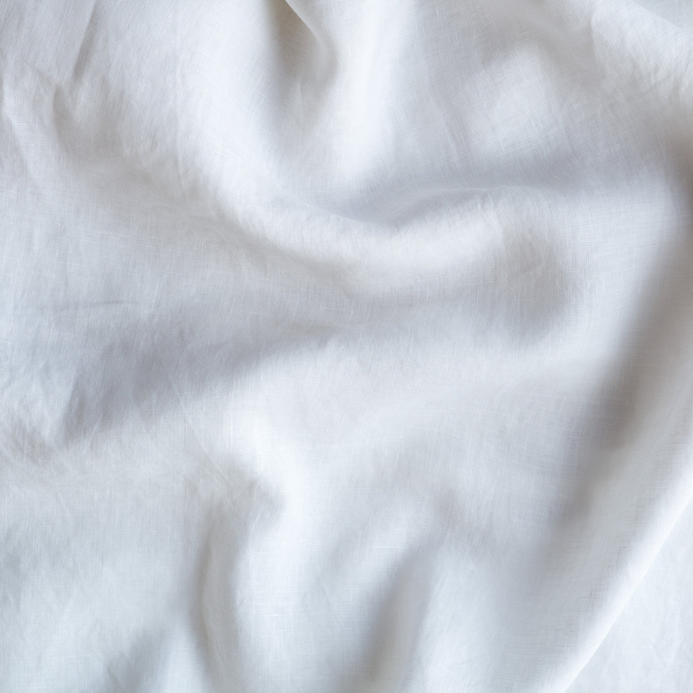Close-up of draped White Bella Notte linen fabric showing soft folds and natural texture.