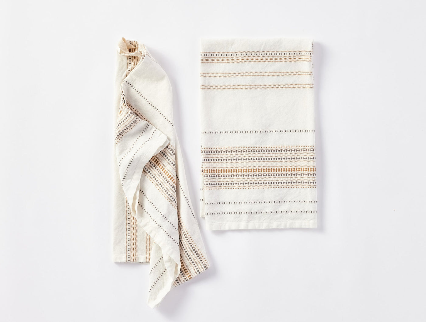 Coyuchi Lobos hand towel pair, one folded flat, one draped, ivory with multicolor stripe detail.