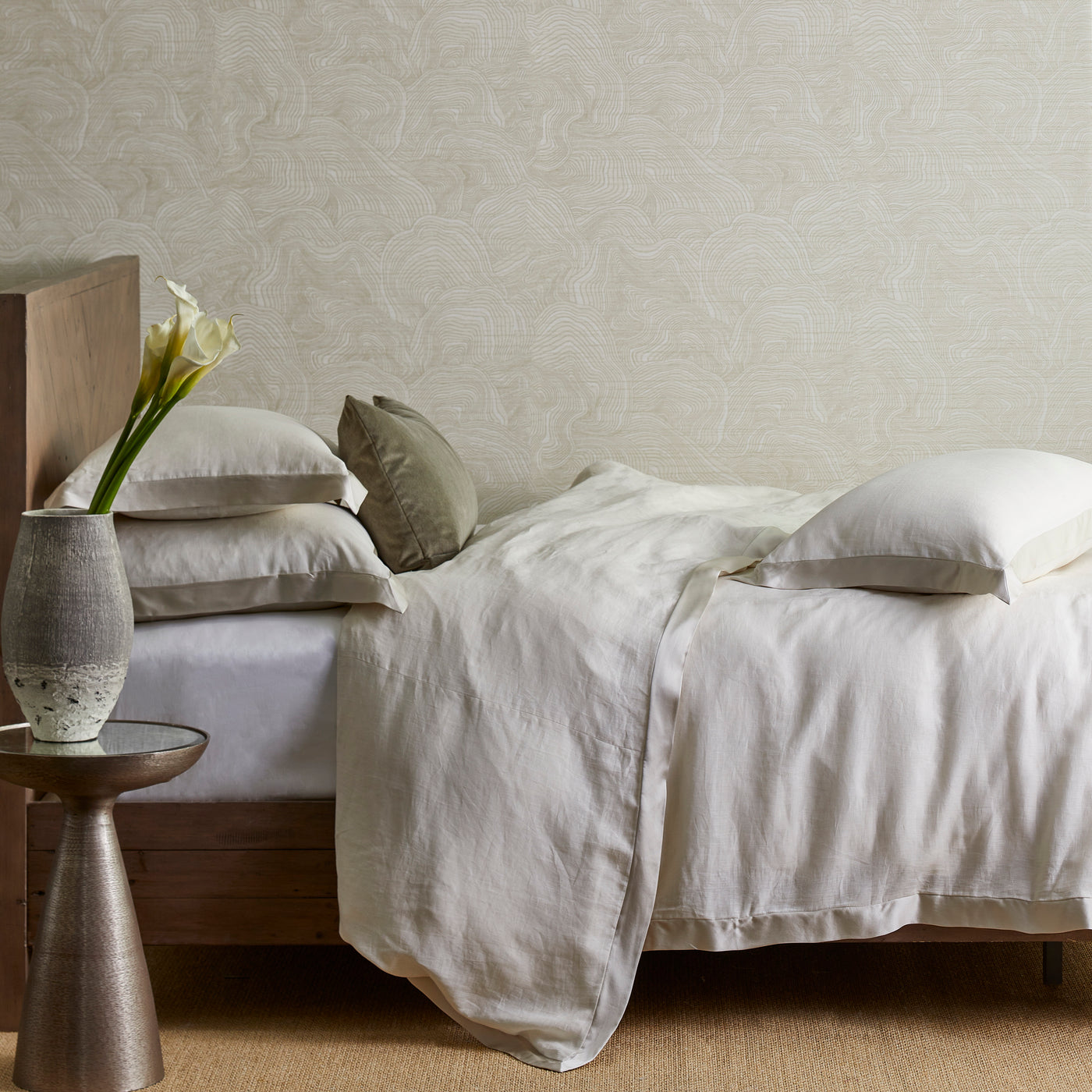 Ivory linen duvet draped over bed with layered neutral pillows in styled bedroom.