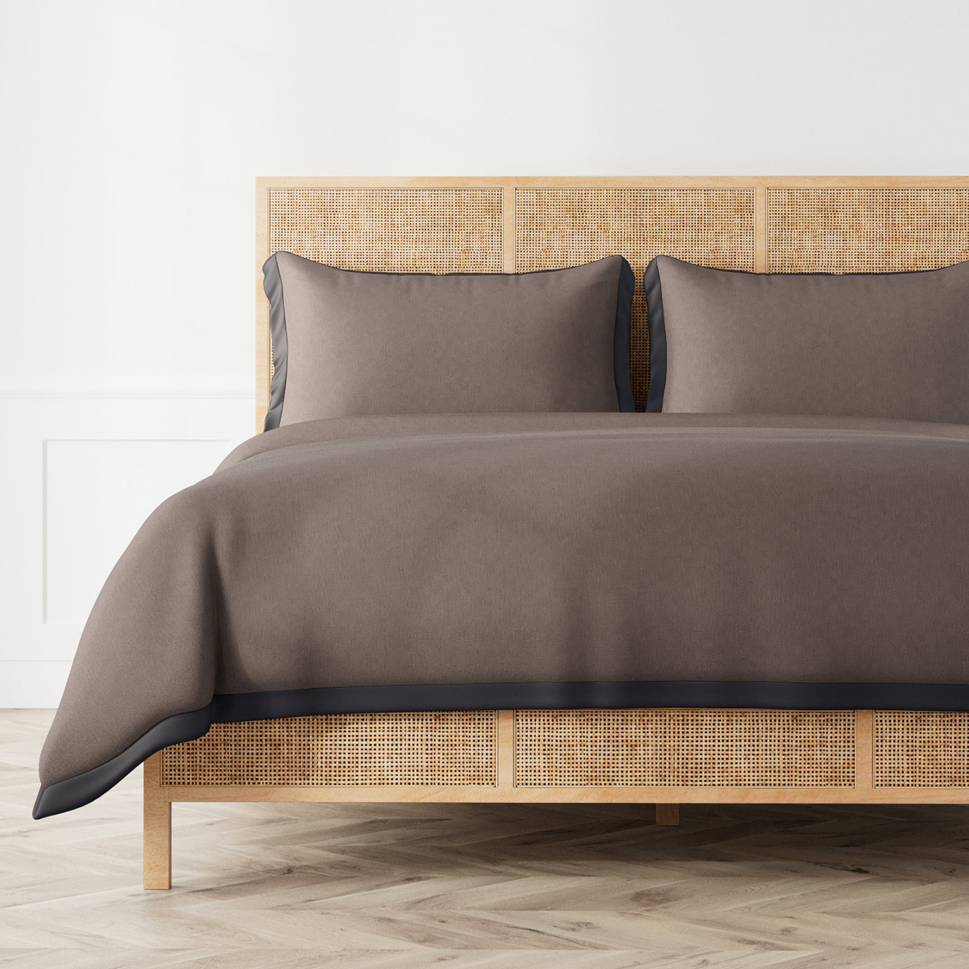 Ann Gish Lover's Kimono duvet cover in taupe with charcoal border trim on rattan bed.