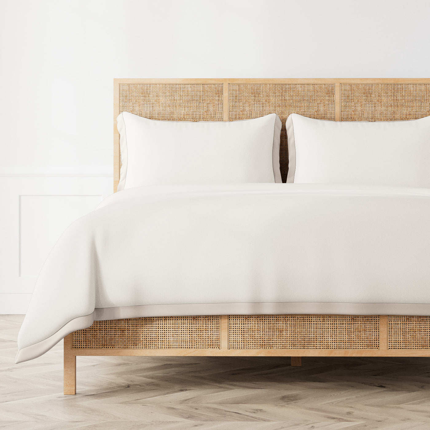 White Ann Gish Lover's Kimono duvet cover styled on a rattan bed, angled view.