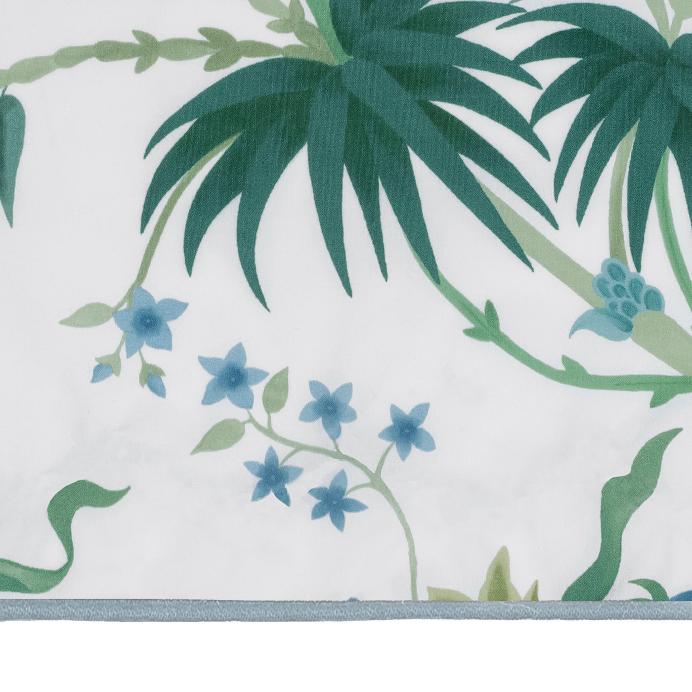 A close-up of the Matouk Palmyra Tissue Box Cover, featuring green palm leaves and blue flowers on a white background—a perfect island-inspired accent for your space.