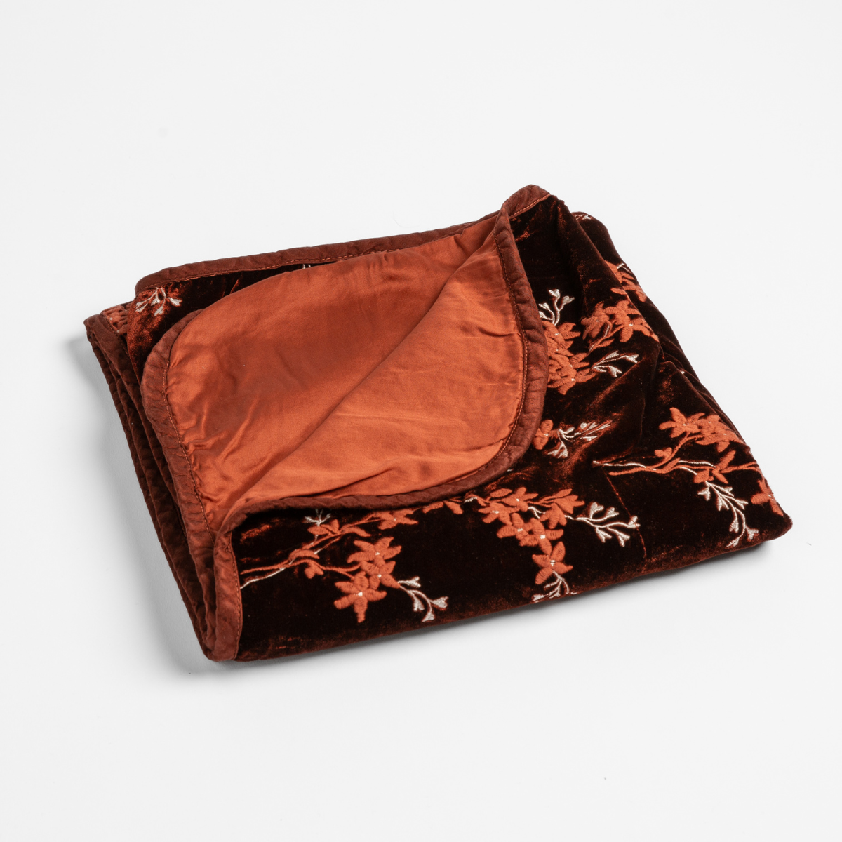 Folded Autumn velvet baby blanket with floral embroidery and satin lining revealed at corner.