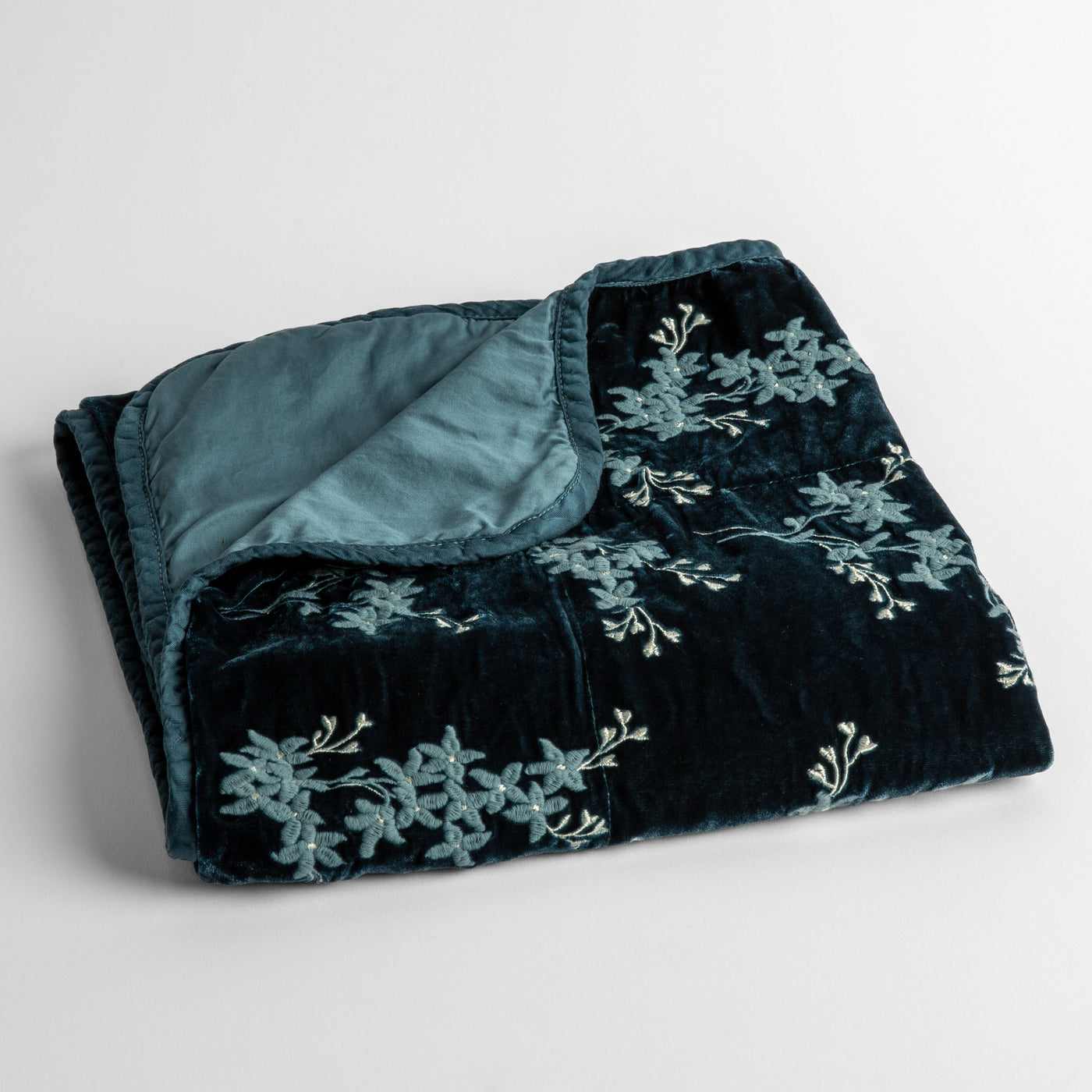 Folded Cenote velvet baby blanket with floral embroidery and contrasting satin reverse.
