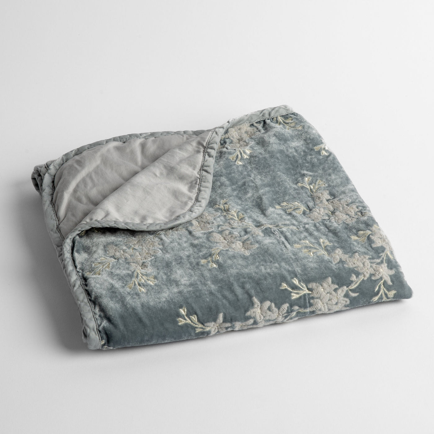 Folded Cloud velvet baby blanket with ivory floral embroidery and silver reverse, corner turned.