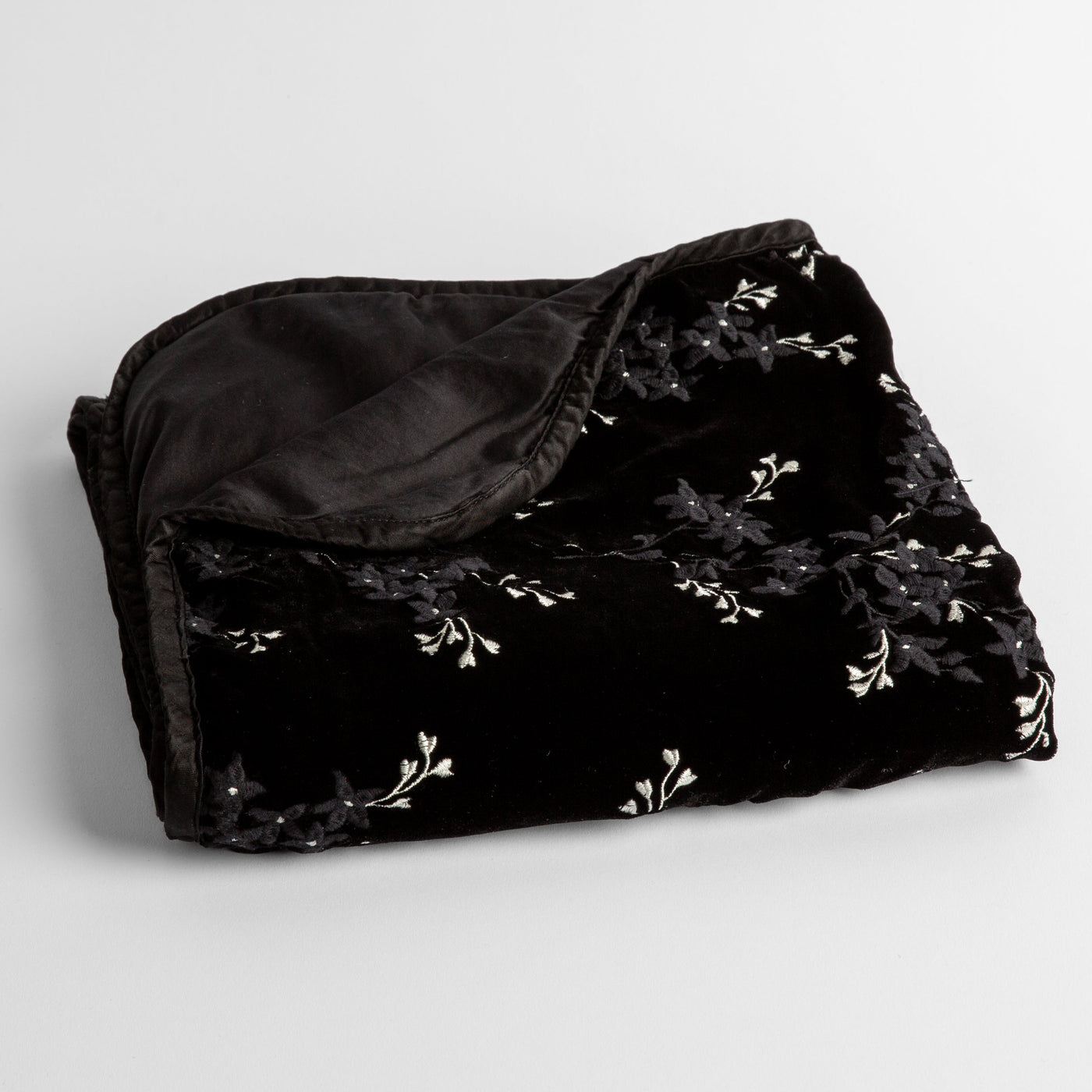 Bella Notte Lynette baby blanket in Corvino, folded to show white floral embroidery on black velvet.
