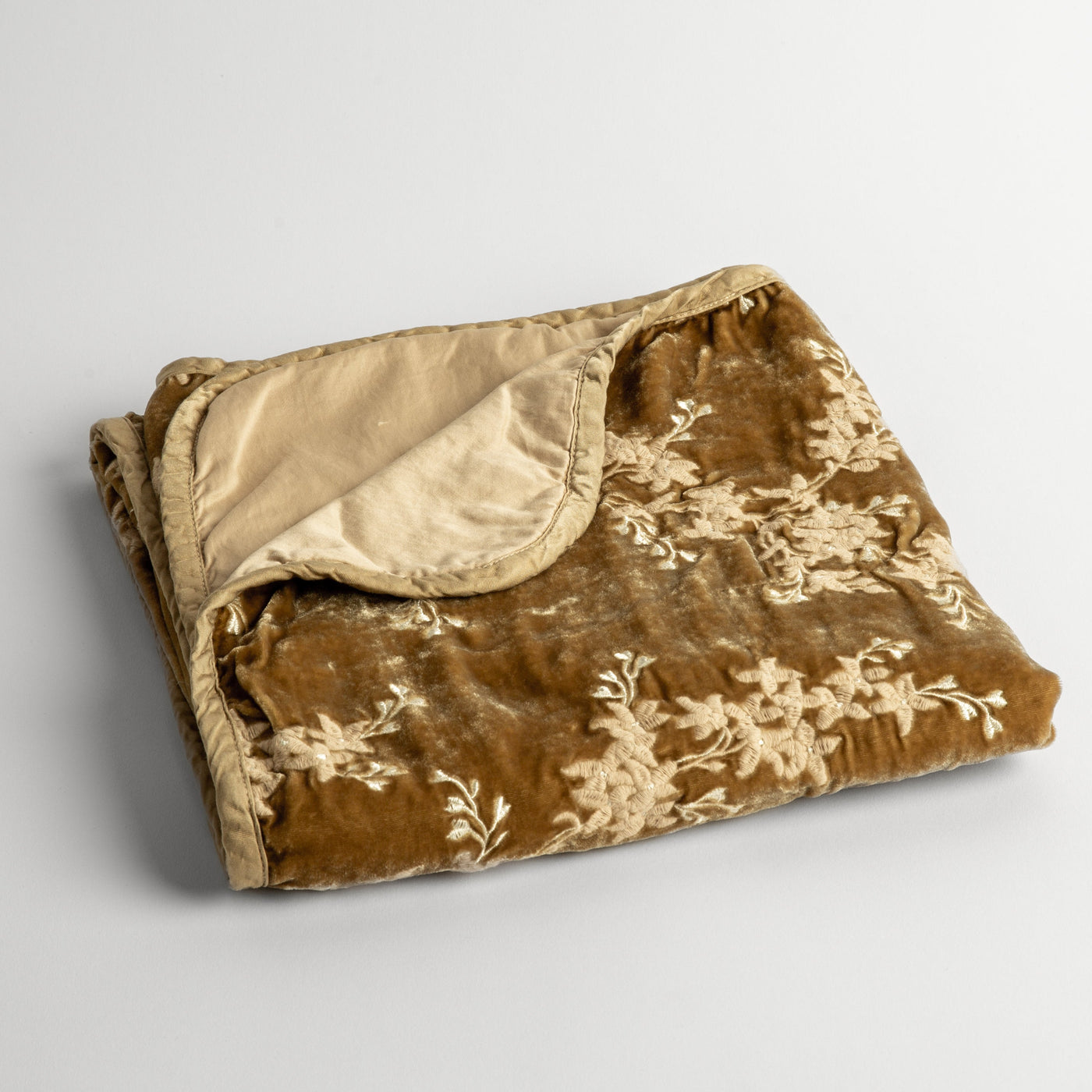 Folded Honeycomb velvet baby blanket, ivory floral embroidery on top, cream satin reverse visible at corner.