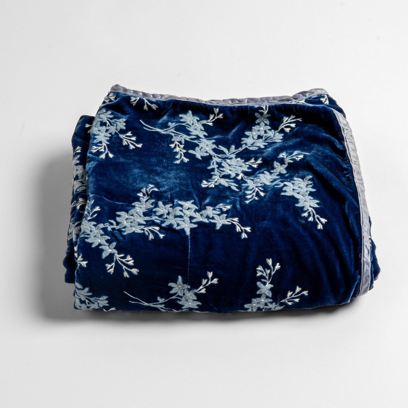 Folded Tahoe Blue velvet baby blanket with pale blue floral embroidery and trim detail.