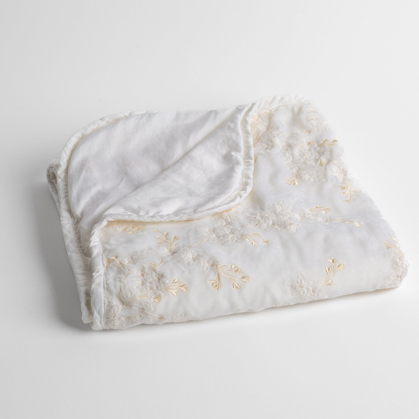 Bella Notte Lynette baby blanket in White with floral embroidery and ruffled trim, folded.
